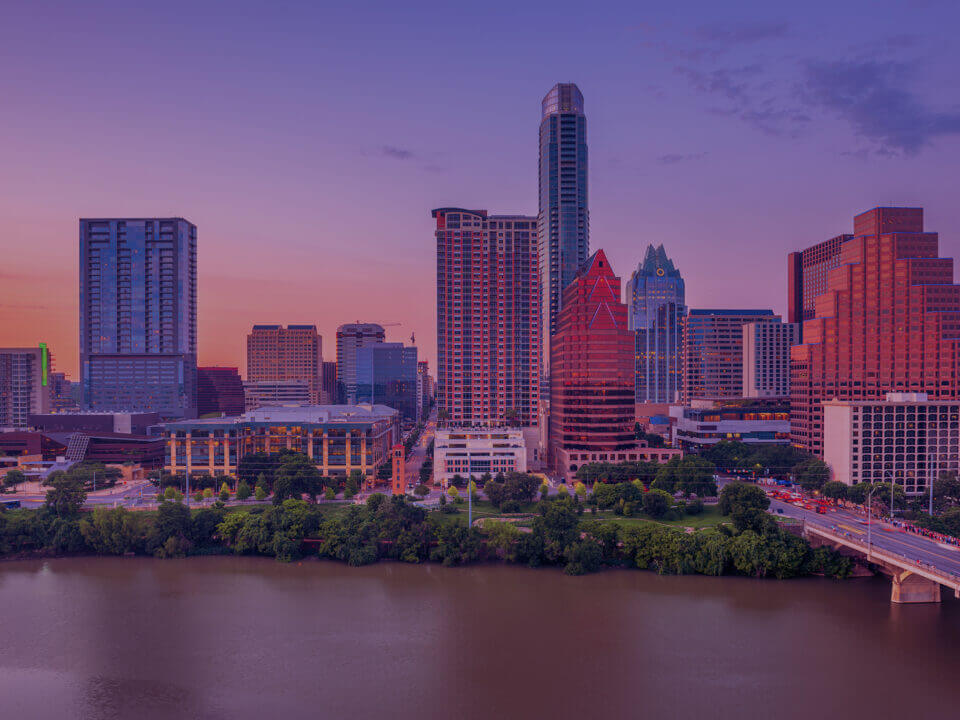 Venture-Forge-Austin-Skyline.jpg - Venture Forge Austin city skyline at sunset, with buildings reflecting warm hues and a river in the foreground.