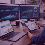 Amazon Ads KPI Tracking and Performance Analysis - Venture Forge Marketing professional analysing Amazon Ads performance dashboards on multiple screens using a tablet in a modern office workspace