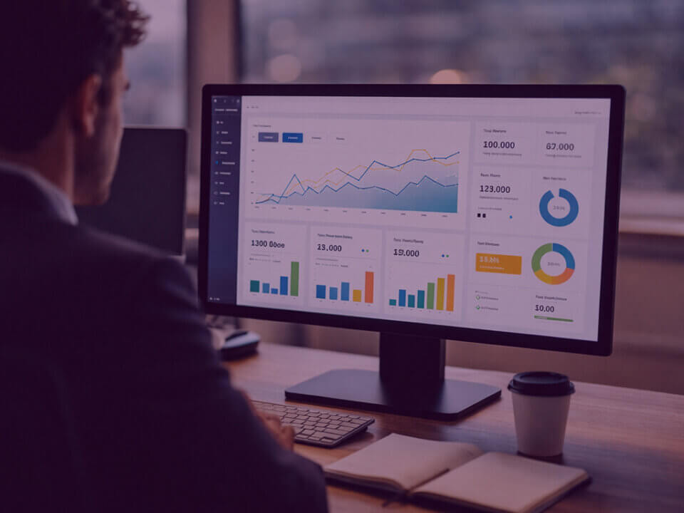 Business professional viewing a performance dashboard on a desktop monitor in a modern office workspace