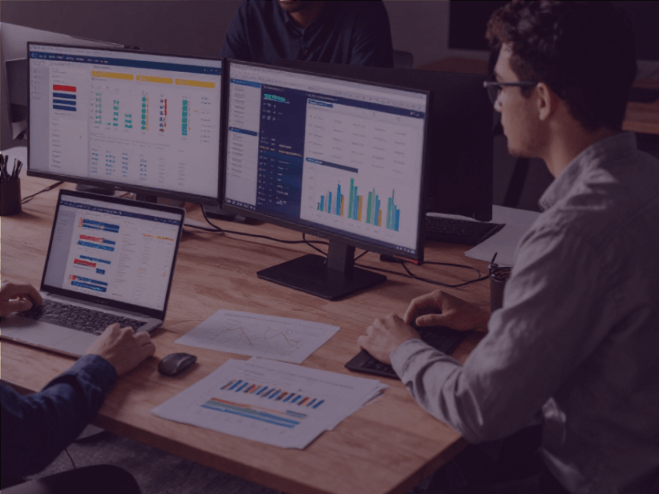 What your Prime Day Performance Data is really telling you Venture Forge - Venture Forge Team of two analyzing data on three screens and a laptop, with charts and graphs on the desk.